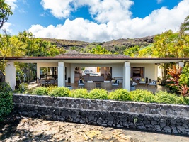 Covered lanai and lounge zones open toward the water and mountains beyond—classic indoor-outdoor island living.