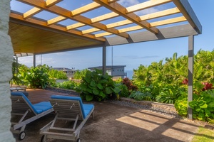 Relaxing lanai with lounge chairs under a pergola, surrounded by lush greenery and offering serene views.