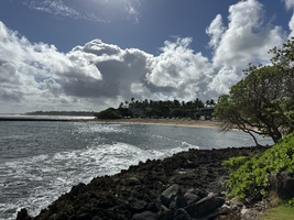 Rocky coastline with bright clouds and calm water.