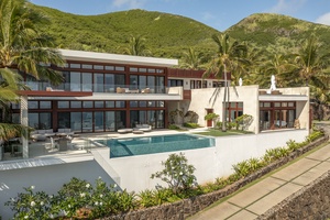 Expansive estate showcasing a modern design, infinity pool, and lush mountain backdrop.