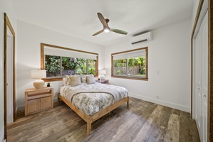 Guest bedroom with queen bed, A/C, and large windows letting in natural North Shore light.