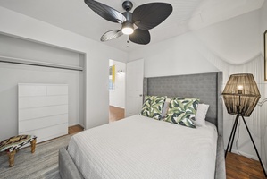 Comfortable guest suite with a plush queen bed, ceiling fan, and soft neutral tones for a tranquil escape.
