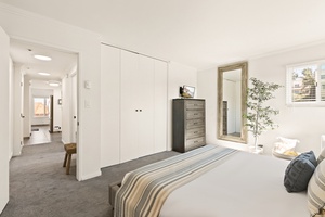 The primary bedroom has cozy bedding and natural light, perfect for a restful night’s sleep.