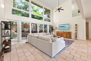 Relax in your bright, airy living room with soaring ceilings and floor-to-ceiling windows overlooking lush tropical gardens.