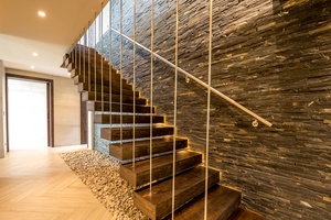 Stylish staircase and a stone accent wall, wooden steps, and modern lighting, adding a touch of sophistication to the space.