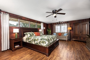 Unwind in your spacious primary suite with rich wood tones, a plush king bed, and a cozy seating area. High windows and tropical-inspired bedding create a serene, island-inspired retreat.
