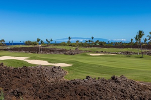 This stunning view captures the essence of a premier golf course, beautifully landscaped and nestled between the volcanic rock and the deep blue of the ocean.