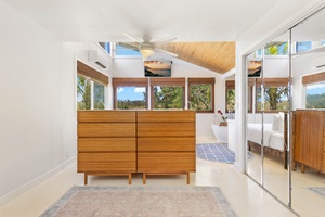 The primary bedroom offers warm wood ceilings, abundant light, and direct lanai access.