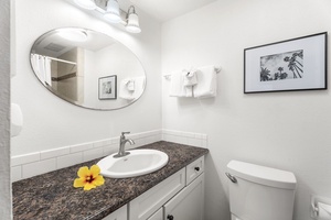 Well-lit guest bathroom featuring granite countertops and thoughtful island decor.