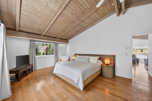 Rest easy in the spacious primary bedroom with a Cal king bed, warm wood ceilings and island-inspired design.