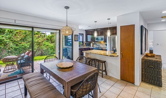 The open-concept dining area and kitchen at Wailea Ekolu 1605 seamlessly connect to the lanai and garden views.