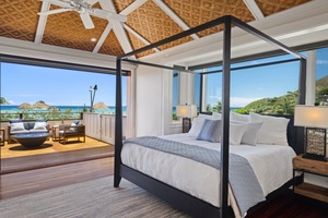 Relax on the primary suite featuring high-vaulted ceiling, four-poster king-sized bed, expansive private lanai with panoramic views.