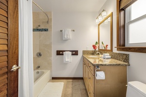 En-suite bathroom to the second bedroom, featuring a granite vanity and tiled shower/tub combo.