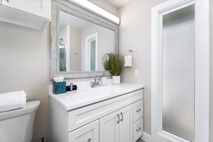 Upstairs bathroom with single vanity and wide mirror, located near guest bedrooms.