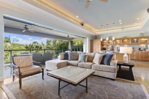 This open-concept living area offers seamless indoor-outdoor living with a spacious sectional and views of the lush surroundings.