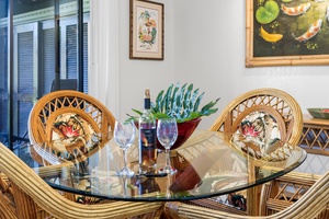 Settle into tropical elegance at your dining table, where wicker chairs and wine glasses await your memorable meals together.