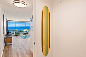 A decorative surfboard adds coastal charm to Mahana 718’s hallway, leading to the living area.