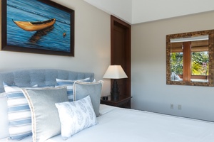 Unwind in your serene bedroom with coastal artwork and soft blue linens creating the perfect tropical escape atmosphere.