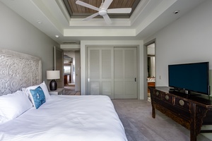 Guest bedroom with a comfortable king-sized bed, ceiling fan, and ample storage.