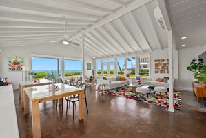 Relax in this bright, open living space with soaring vaulted ceilings, colorful accents, and floor-to-ceiling windows framing stunning ocean views—your perfect coastal retreat.