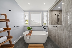 Primary bathroom with freestanding soaking tub, custom walk-in shower, and elegant window-framed privacy.