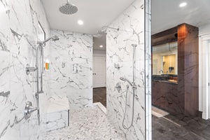 Spa-style shower in the primary suite features dual rainfall heads and elegant stonework.
