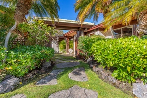 Stone path leads to the front door through lush landscaping.