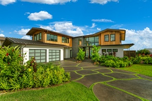 Modern architectural home featuring mixed materials and tropical landscaping under bright blue skies.