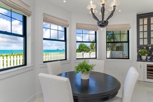 Intimate breakfast nook with panoramic windows overlooking turquoise waters.
