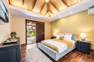Warmly lit guest bedroom with high ceilings, split AC, and direct outdoor access.