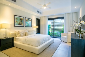 Inviting guest bedroom with a cozy bed and garden views through large windows.