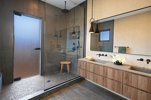 Guest bath featuring glass shower, rainfall head, and dual vanities.
