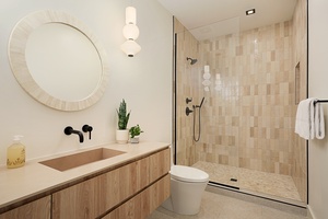 Warm-toned guest bath featuring elegant fixtures and a spacious glass walk-in shower for a refreshing island reset.