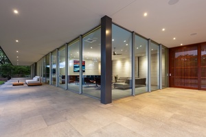 The modern glass entrance opens to the luxurious living and dining areas of the home.