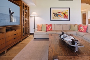 Sink into plush seating surrounded by warm wood tones and vibrant art, perfect for movie nights or quiet moments.