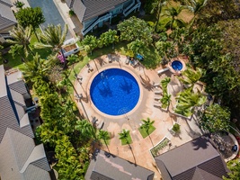 Aerial view of the resort's main swimming pool surrounded by tropical palm trees and sun loungers on spacious deck.