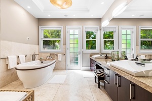 Primary suite bathroom with soaking tub, dual vanities & lanai access.
