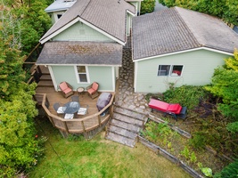 A bird’s-eye view of the house reveals a lovely outdoor patio area, perfect for relaxing or sharing meals amidst a lush garden setting.