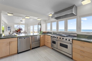 The kitchen has stunning sea views through expansive windows in this modern kitchen featuring professional-grade appliances and sleek finishes.