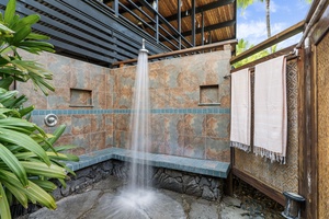 Refresh under the tropical sky in this stunning open-air shower, where natural stone meets lush greenery for your private paradise.