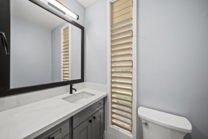 Bathroom with a sleek vanity, louvered window, and updated fixtures for a clean, modern style.
