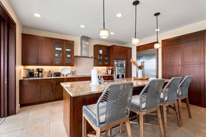 Alternate view of the e rich wooden cabinets and stainless steel appliances.legant kitchen with wooden cabinetry and modern pendant lighting.