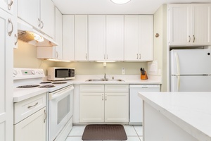 Ample appliances and tools with white cabinetry & counters.