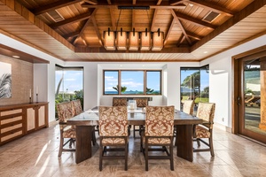 Indoor dining under a striking wood-beam ceiling with lush garden and ocean views.