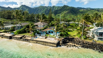 Beachfront home set along the shoreline with mountain views and tropical surroundings.