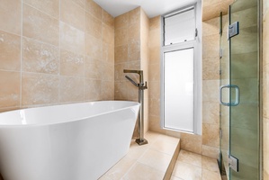 Contemporary glass shower and tilework provide a sleek, comfortable setting, combining function with a luxury feel.