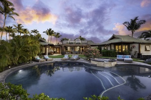 Luxurious home with a large pool, surrounded by tropical landscaping and lounge chairs.