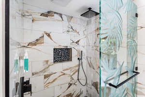Step into your luxurious marble shower with rainfall showerhead and tropical glass accents for a spa-like experience.