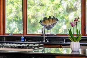 Modern kitchen with a decorative centerpiece by the window, offering a serene view of lush greenery while preparing meals.