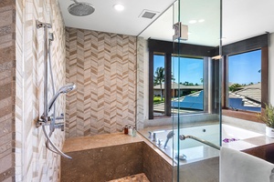 Spa-style ensuite with dual rainfall showers and soaking tub with a view.